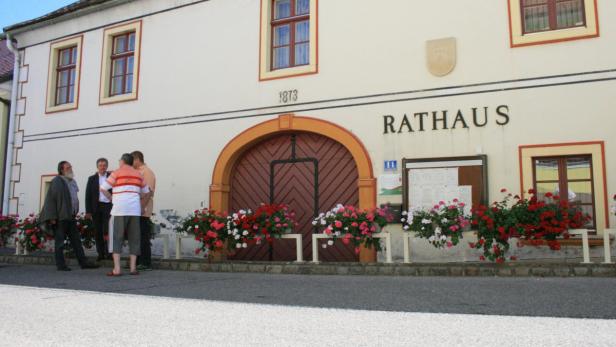 Vor dem Rathaus aus dem Jahr 1873 stehen mehrere Personen und unterhalten sich.