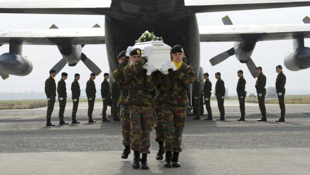 Soldaten tragen einen Sarg vor einem Militärflugzeug.