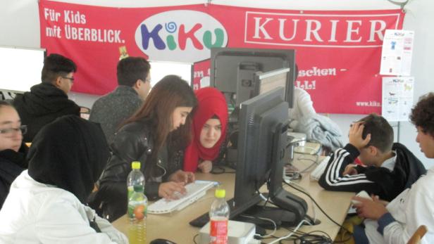 Eine Gruppe von Jugendlichen sitzt an Computern unter einem „KiKu“-Banner.