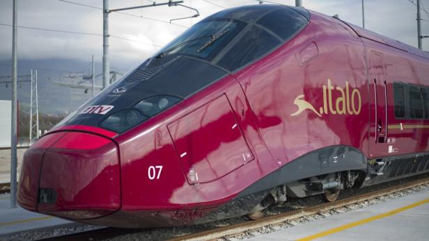 Ein roter Hochgeschwindigkeitszug der Marke Italo auf einem Gleis.
