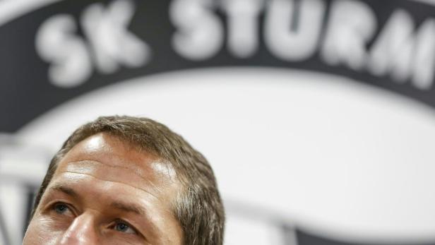 Ein Mann blickt nach oben, im Hintergrund das Logo des SK Sturm Graz.