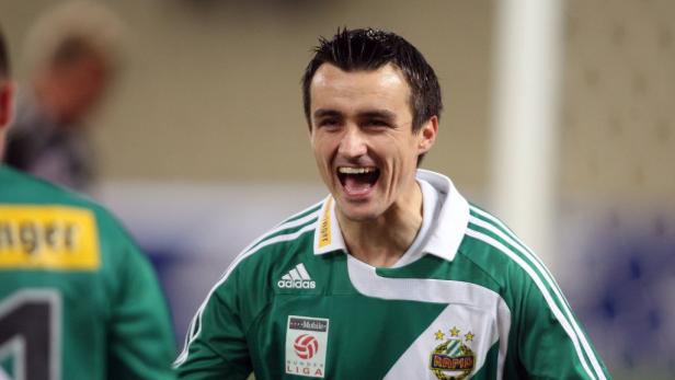 Ein lachender Fußballspieler im grün-weißen Trikot von Rapid Wien.
