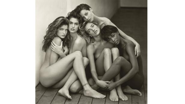 Fünf Models posieren in einer Schwarzweißaufnahme eng aneinander geschmiegt auf einem Holzboden.