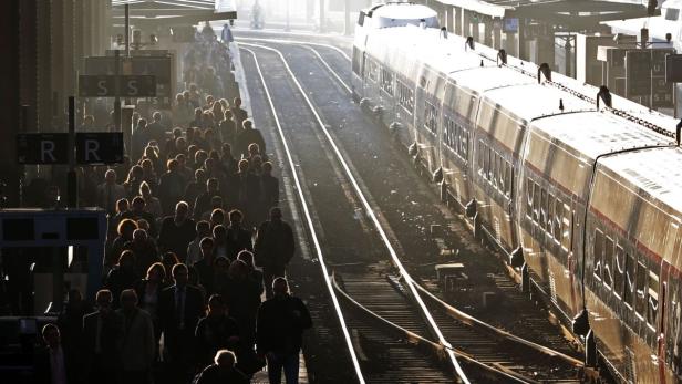 Menschen warten auf einem Bahnsteig neben einem Zug.