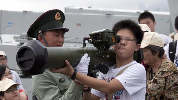 epa03199028 A member of China&#039;s People Liberation Army (PLA) helps a visitor with an anti-tank weapon during an &#039;open barracks day&#039; at the Ngong Shuen Chau Naval Base, part of the Hong Kong Garrison, in Hong Kong, China, 28 April 2012. The Hong Kong Garrison includes elements of the People&#039;s Liberation Army Ground Force, PLA Navy, and PLA Air Force, comprises about 6000 personnel. EPA/JEROME FAVRE