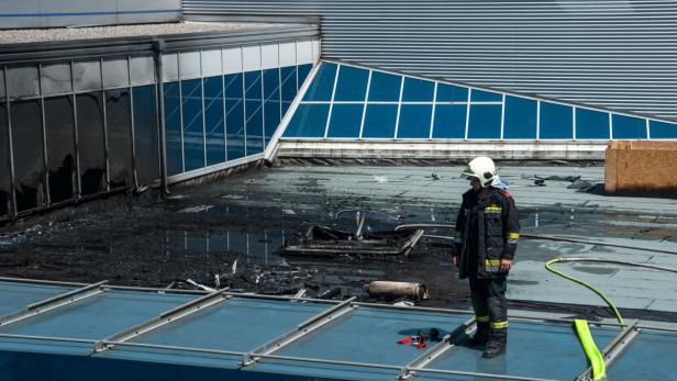 Ein Feuerwehrmann steht auf dem Dach eines Gebäudes nach einem Brand.
