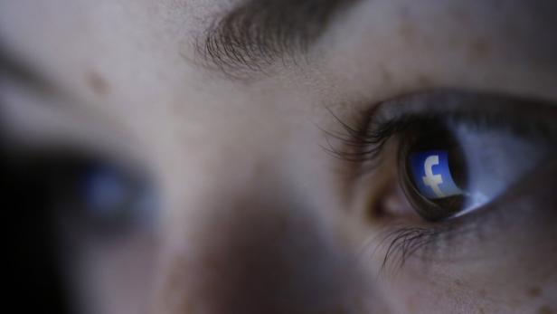 Das Facebook-Logo spiegelt sich im Auge einer Person.