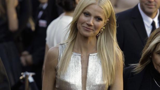 Gwyneth Paltrow lächelt in einem silbernen Kleid auf dem roten Teppich.