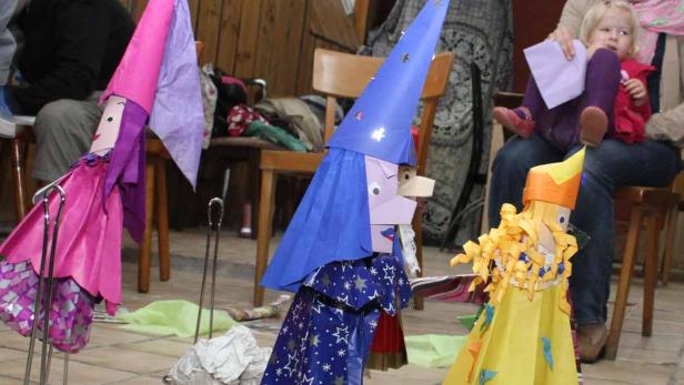 Kreative, selbstgemachte Hexenfiguren stehen in einem Raum, während eine Frau mit einem Kind zusieht.