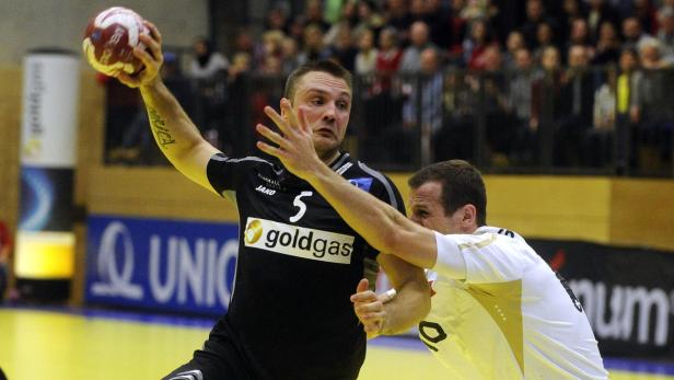 Ein Handballspieler im schwarzen Trikot mit der Nummer 5 wirft den Ball.