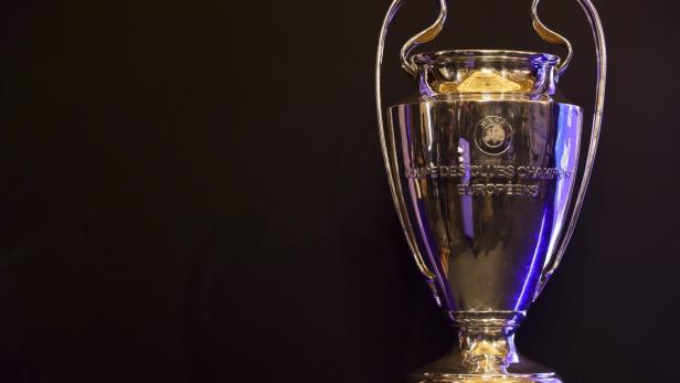 Die Trophäe der UEFA Champions League auf einem Sockel vor schwarzem Hintergrund.