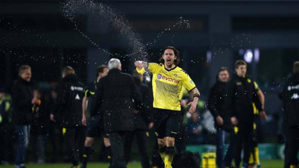 Ein Fußballspieler im gelben Trikot wird mit Wasser überschüttet.