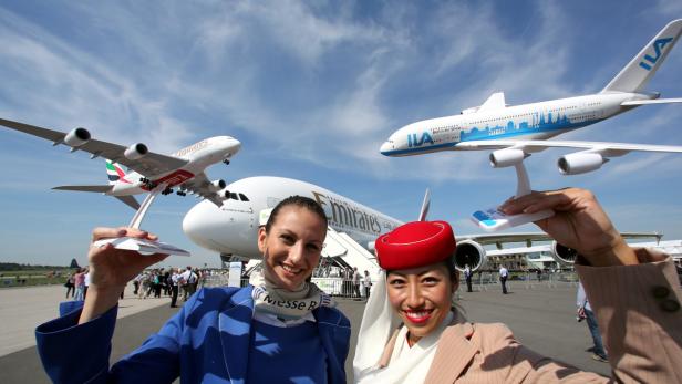 Zwei Flugbegleiterinnen posieren mit Flugzeugmodellen vor einem Airbus A380.