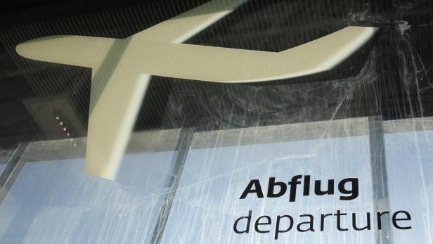 Ein Flugzeugsymbol und der Schriftzug „Abflug“ an einem Fenster.