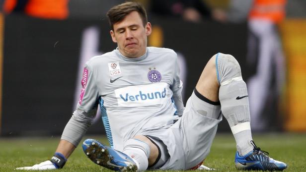 Ein Fußballspieler sitzt erschöpft auf dem Rasen.