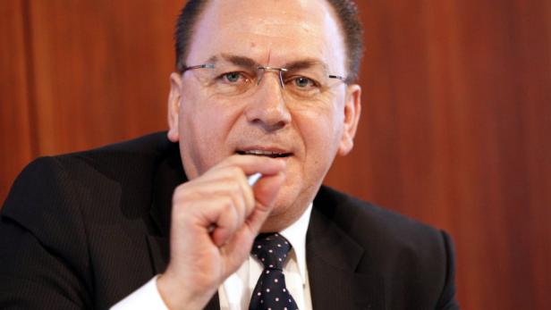 Ein Mann mit Brille und Anzug hält einen Stift in der Hand.