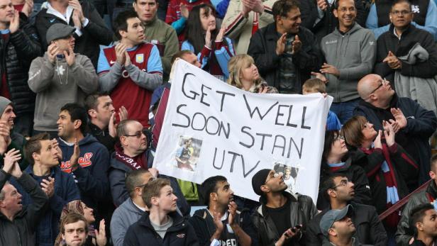 Fußballfans halten ein Transparent mit der Aufschrift „Get Well Soon Stan UTV“.