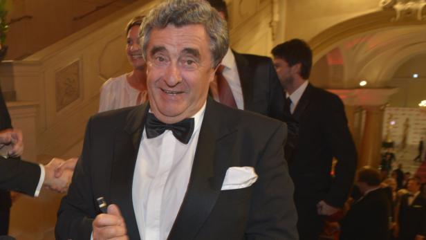 Ein Mann im Smoking lächelt auf einer Veranstaltung.