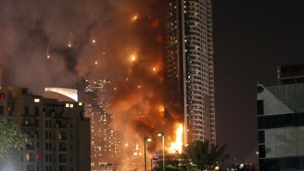 Ein Hochhaus steht in Flammen, Rauch steigt auf.