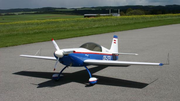 Ein blau-weißes Sportflugzeug steht auf einem Flugfeld.