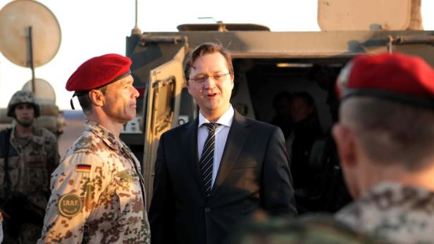 Ein Politiker im Gespräch mit einem Soldaten der Bundeswehr vor einem Militärfahrzeug.