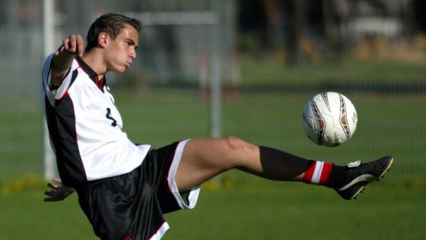 Ein Fußballspieler schießt einen Ball auf einem grünen Feld.