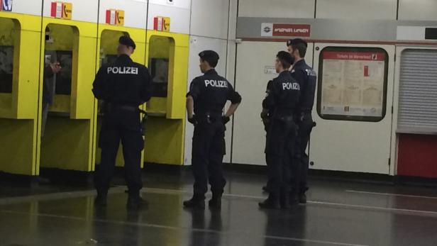 Mehrere Polizisten stehen in einer U-Bahn-Station in der Nähe von Fahrkartenautomaten.