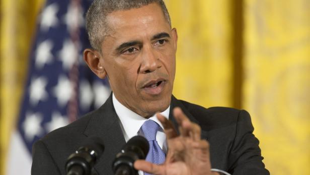 Barack Obama spricht vor einer US-Flagge und einem gelben Vorhang.