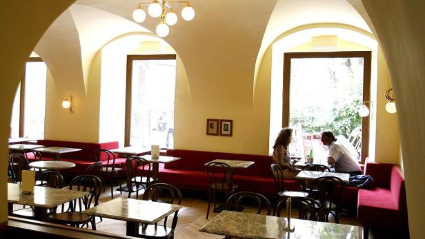 Ein Paar sitzt in einem Café mit Gewölbedecke und roten Sitzbänken.