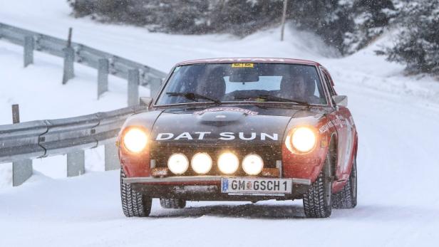 Ein roter Datsun-Rallyewagen fährt auf einer schneebedeckten Straße.