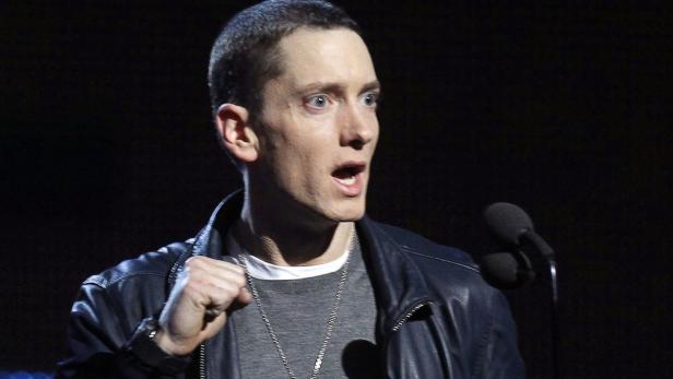 Eminem spricht bei einer Veranstaltung in ein Mikrofon.