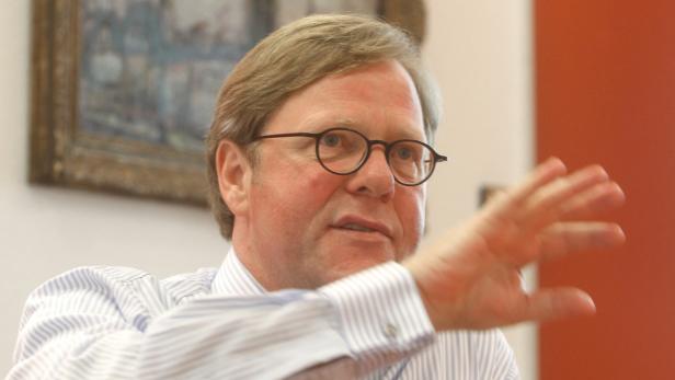 Ein Mann mit Brille gestikuliert mit der Hand.