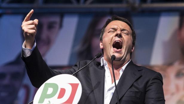 Matteo Renzi gestikuliert und spricht bei einer Rede vor einem Mikrofon.