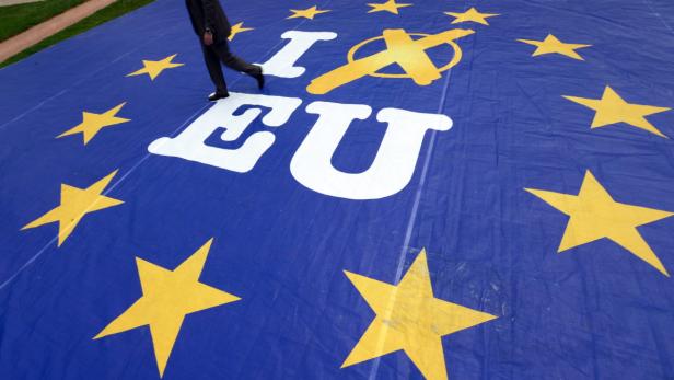 Eine Person geht über eine EU-Flagge mit durchgestrichenem „I“.