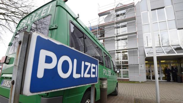 Ein grüner Mannschaftswagen der Polizei steht vor einem Gebäude.