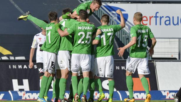 Eine Gruppe Fußballspieler in grünen Trikots feiert einen Sieg.