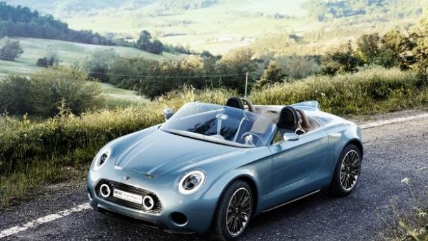 Ein blauer Mini Cooper Roadster fährt auf einer Landstraße.