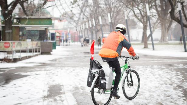 Ein Radfahrer fährt im Winter durch eine verschneite Stadt.