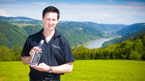 Martin Paminger mit seinem Wodka hoch über dem oberen Donautal. Rechs im Hintergrund ist der Ort Wesenufer zu sehen.