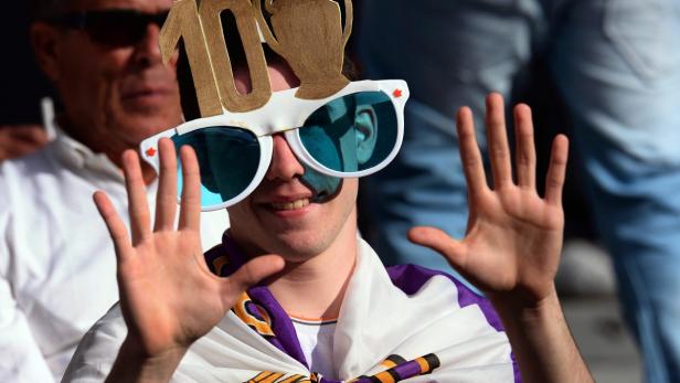 Ein Fan mit einer Schärpe und einer lustigen Brille feiert ein Sportereignis.