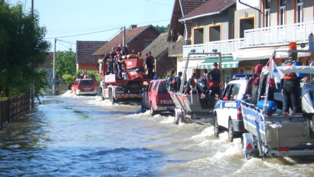 Ein überflutete Straße mit Feuerwehrfahrzeugen und Rettungsbooten.