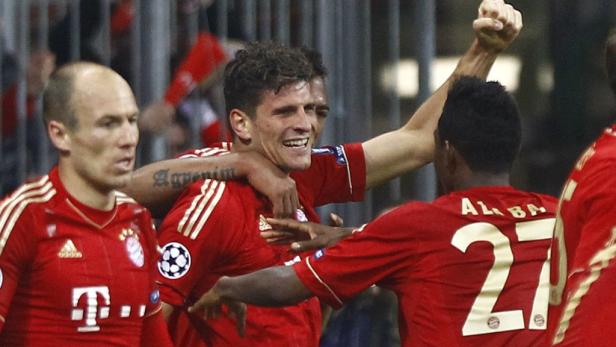 Jubelnde Fußballspieler des FC Bayern München in roten Trikots.