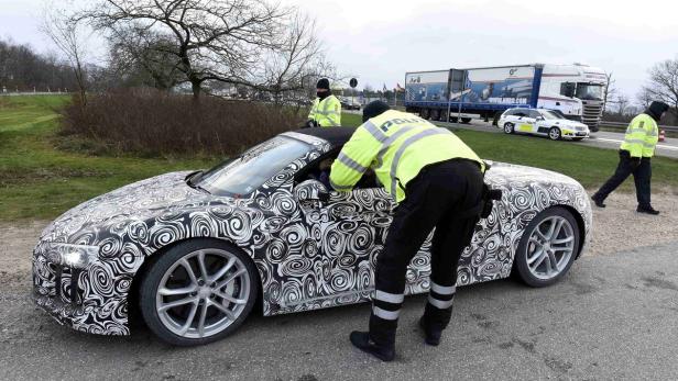 Polizisten kontrollieren ein getarntes Auto am Straßenrand.