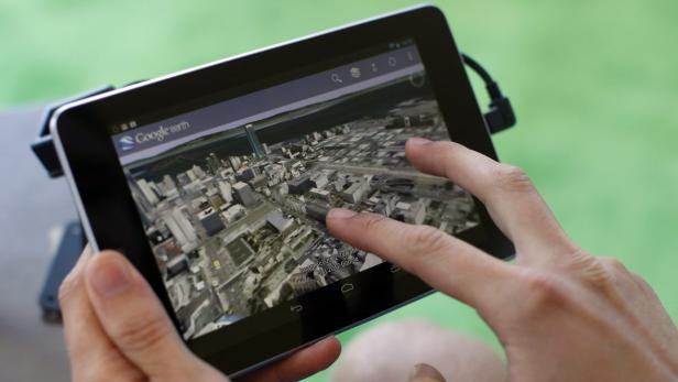 Eine Person nutzt Google Earth auf einem Tablet, um eine Stadtansicht zu betrachten.