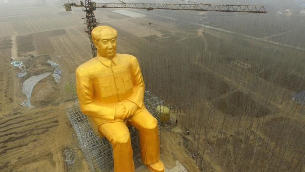 Eine goldene Statue von Mao Zedong sitzt auf einem Gerüst unter einem Baukran.