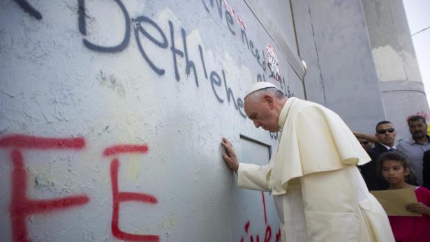 Papst Franziskus berührt eine mit Graffiti bedeckte Mauer in Bethlehem.