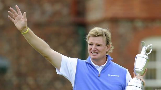Der Golfspieler Ernie Els hält eine Trophäe in der Hand und winkt.