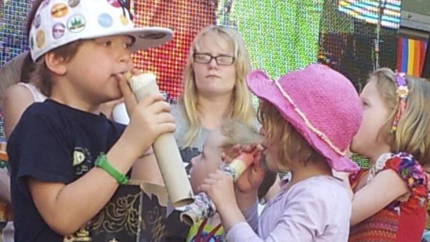 Eine Gruppe Kinder spielt mit selbstgebastelten Tröten.