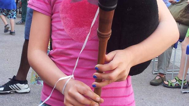 Ein junges Mädchen mit Brille spielt auf einem Dudelsack.