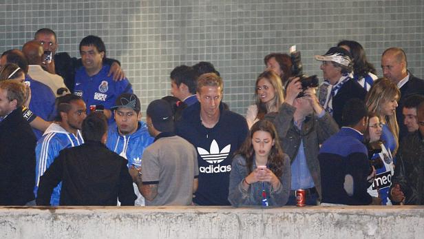 Eine Gruppe von Menschen steht hinter einer Mauer, einige tragen blaue FC Porto-Trikots.